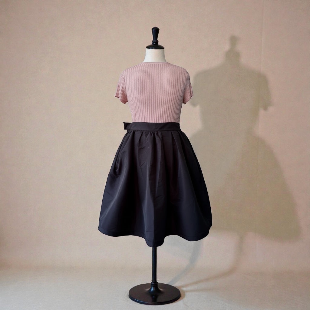 pink ribbed top paired with a high-waisted black flared skirt.