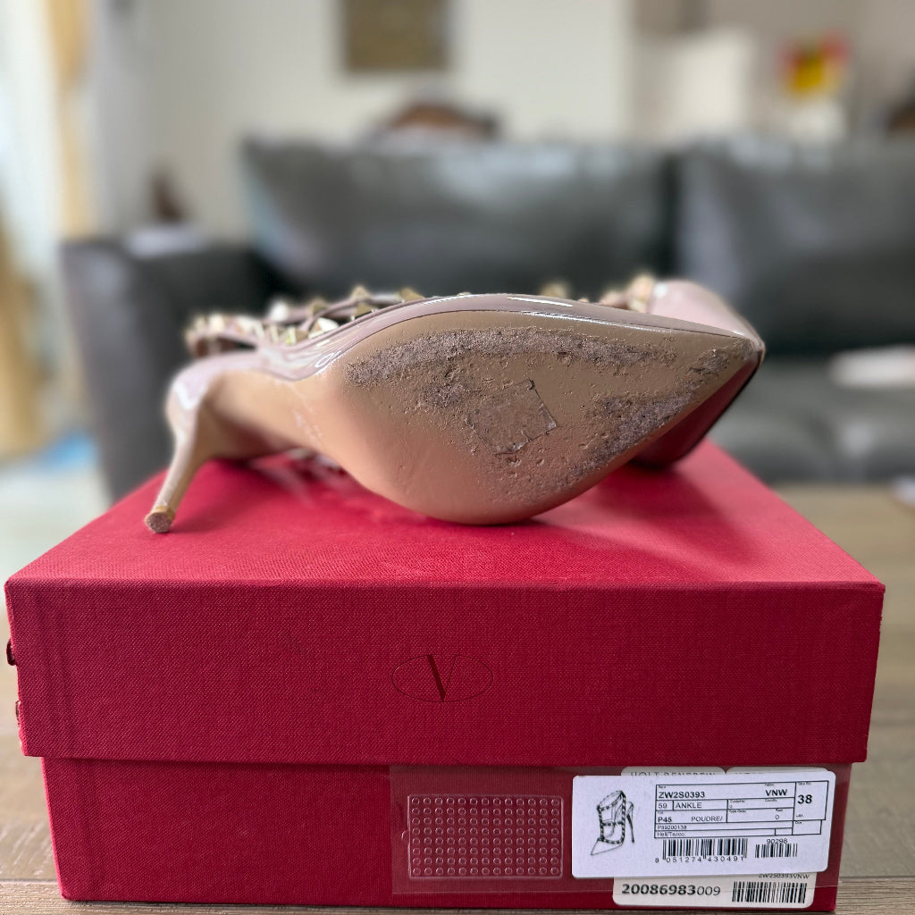 Valentino Garavani Rockstud patent leather pumps in a nude-toned "Poudre" color.